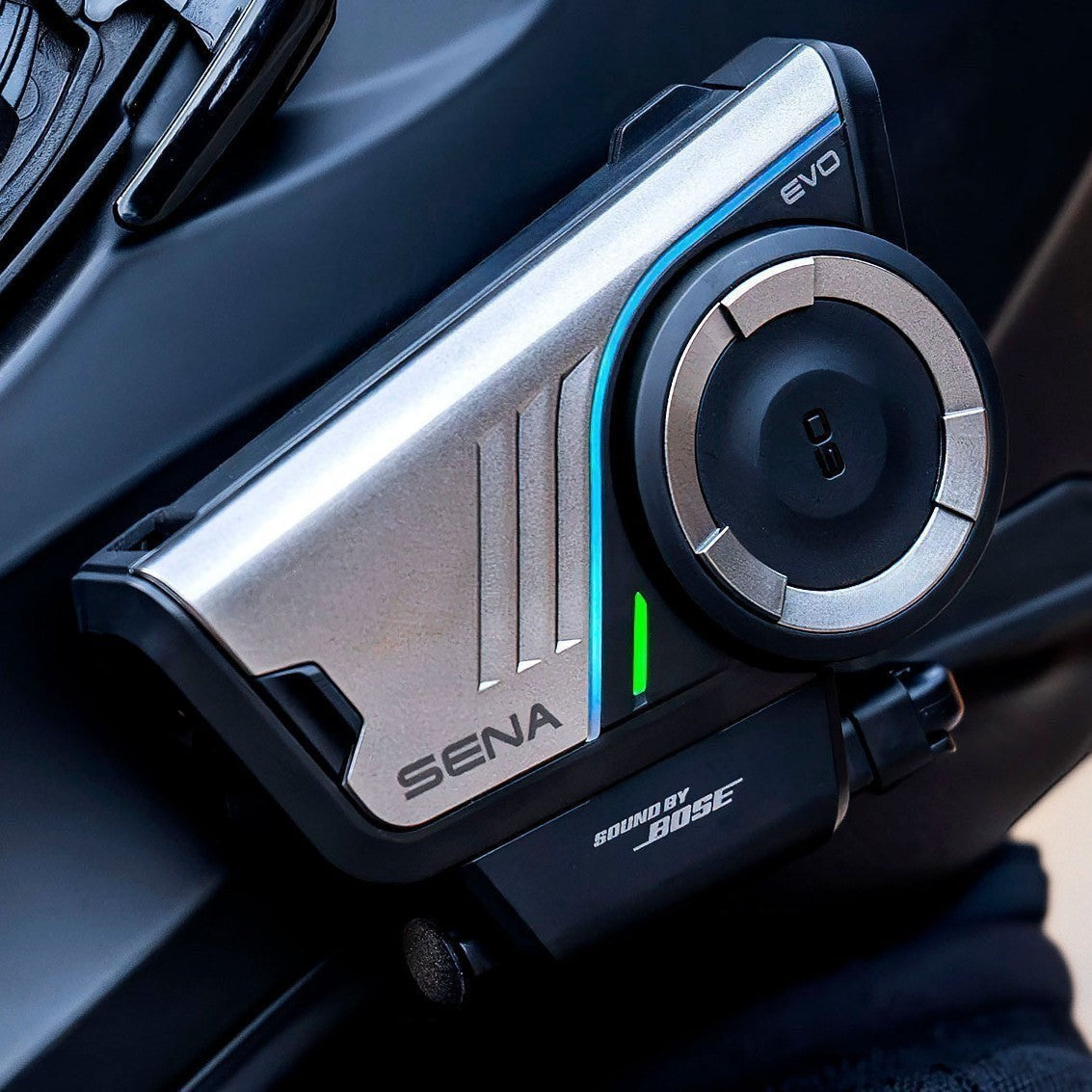 Moto Explorer Sena 60S EVO motorcycle communication system with metallic finish, jog dial, and LED indicator.