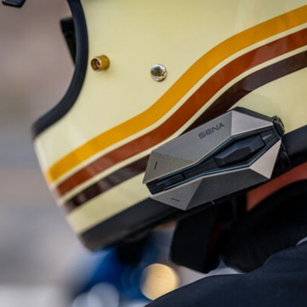 Moto Explorer Sena 60X motorcycle Bluetooth communication system mounted on a retro-style cream helmet with stripes.