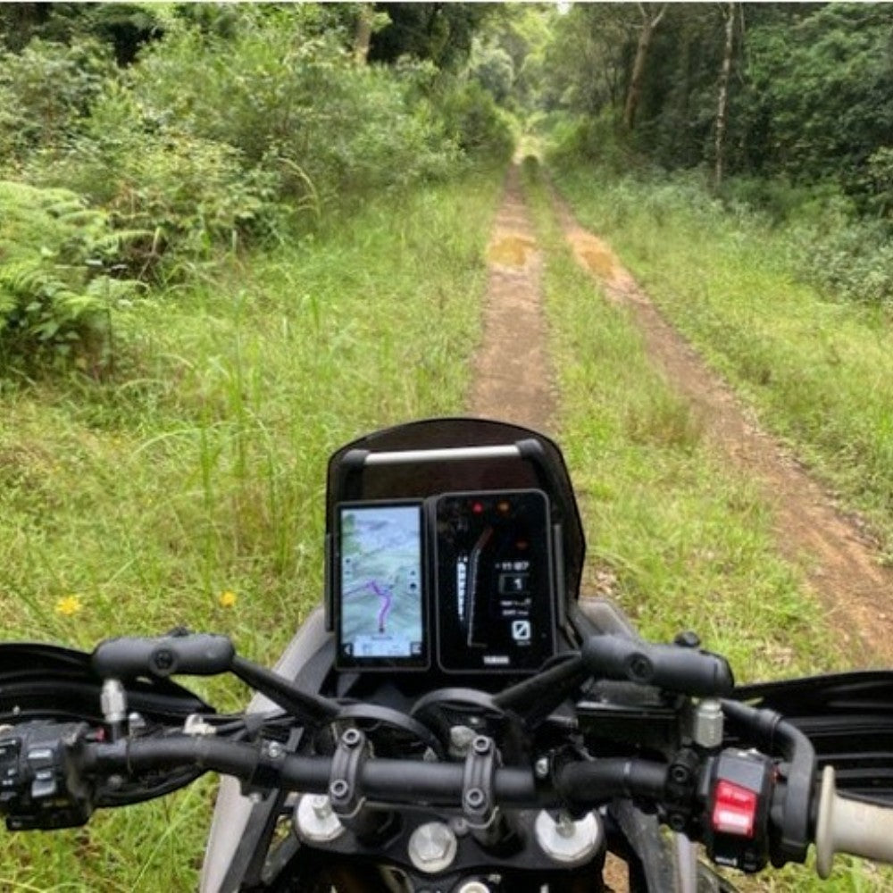 Moto Explorer Garmin side-by-side dash mount on a Yamaha Tenere 700, showing GPS and TFT screen on a forest trail.